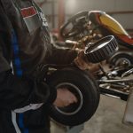 Un mécanicien tient un pneu de karting avec enjoliveur devant un kart en arrière-plan