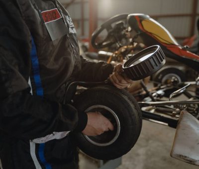 Un mécanicien tient un pneu de karting avec enjoliveur devant un kart en arrière-plan