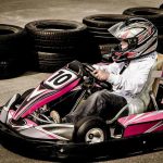 Un conducteur pilote un kart rose sur circuit avec pneus empilés