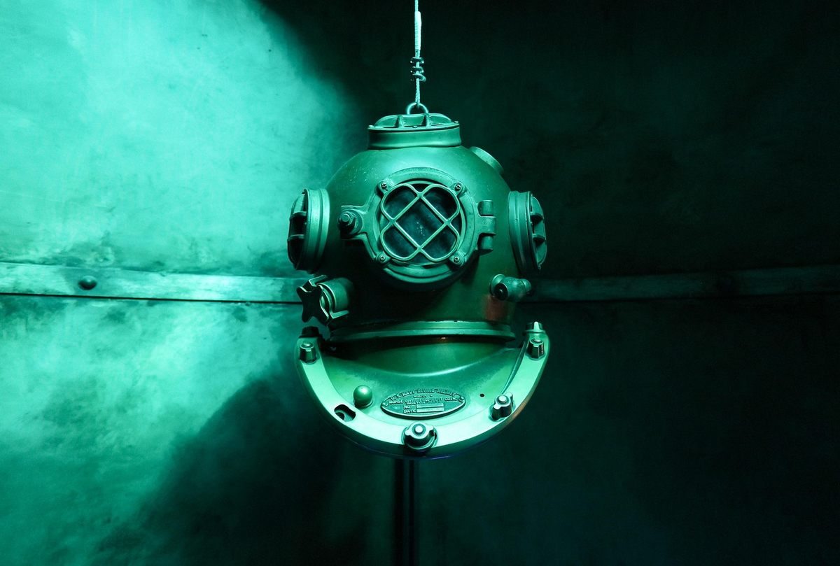 Casque de plongée vert suspendu, éclairage bleu, arrière-plan sombre, détails métalliques visibles