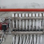 Manifold de chauffage avec tuyaux blancs, vanne et pompe sur mur