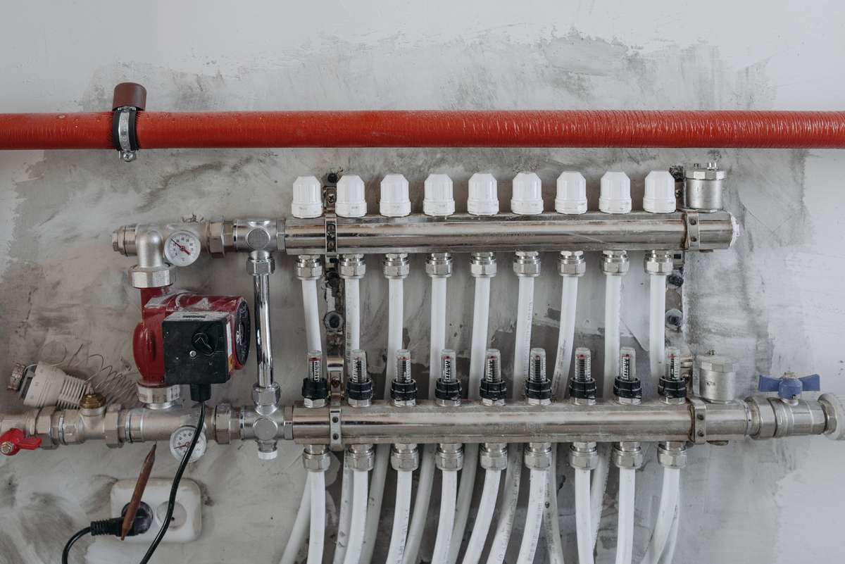Manifold de chauffage avec tuyaux blancs, vanne et pompe sur mur