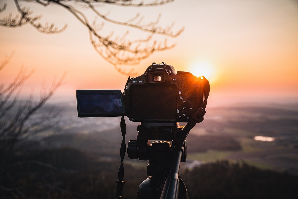 Appareil photo sur trépied face à un coucher de soleil