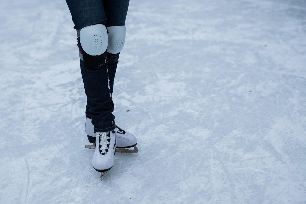 Patins à glace, genouillères et pantalon noir sur une surface glacée Patins à glace, genouillères et pantalon noir sur une surface glacée