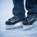 Un individu en jean porte des patins à glace sur la glace