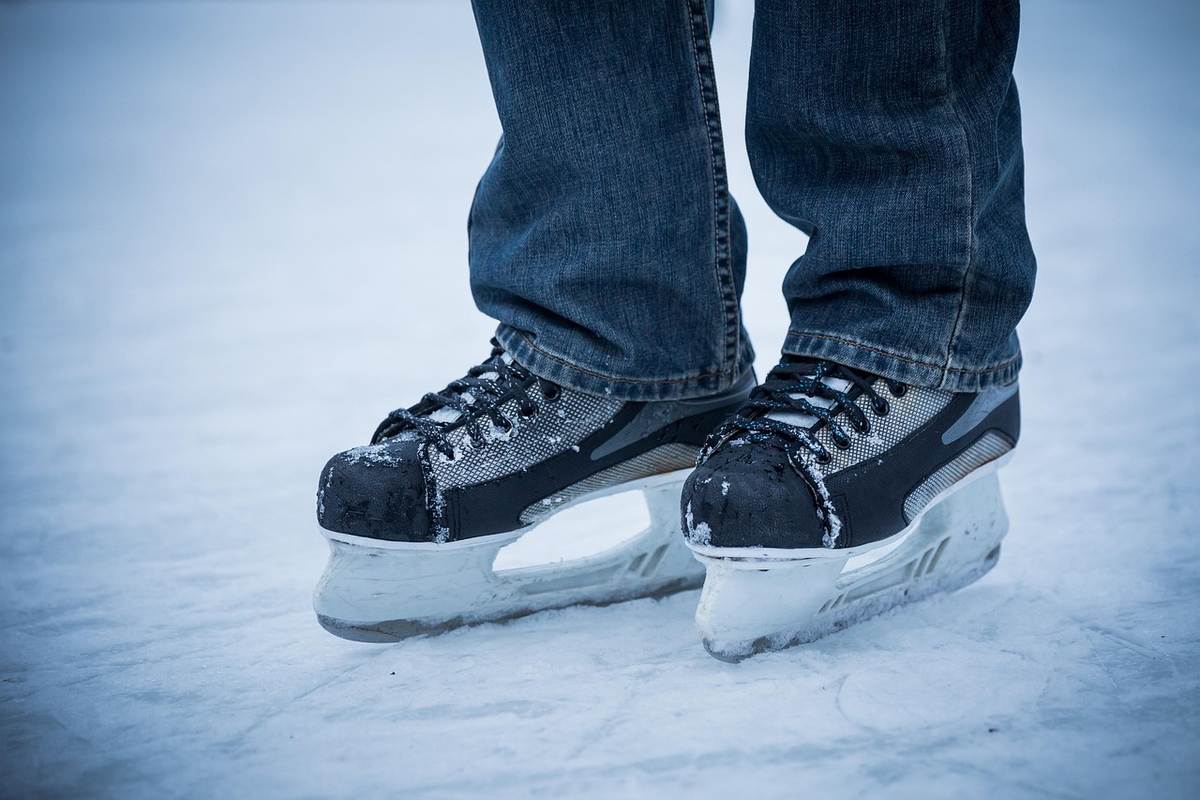 Un individu en jean porte des patins à glace sur la glace
