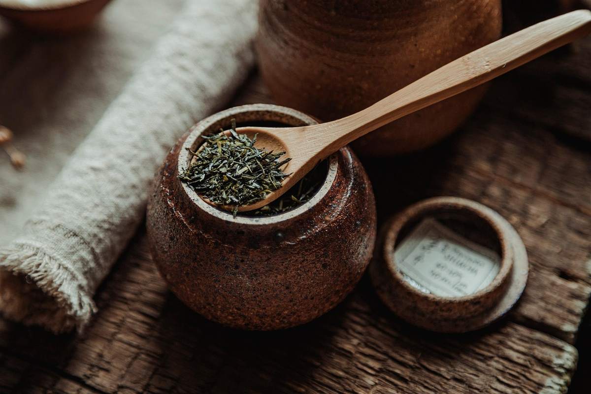 Cuillère en bois dans un pot en terre cuite contenant des herbes séchées