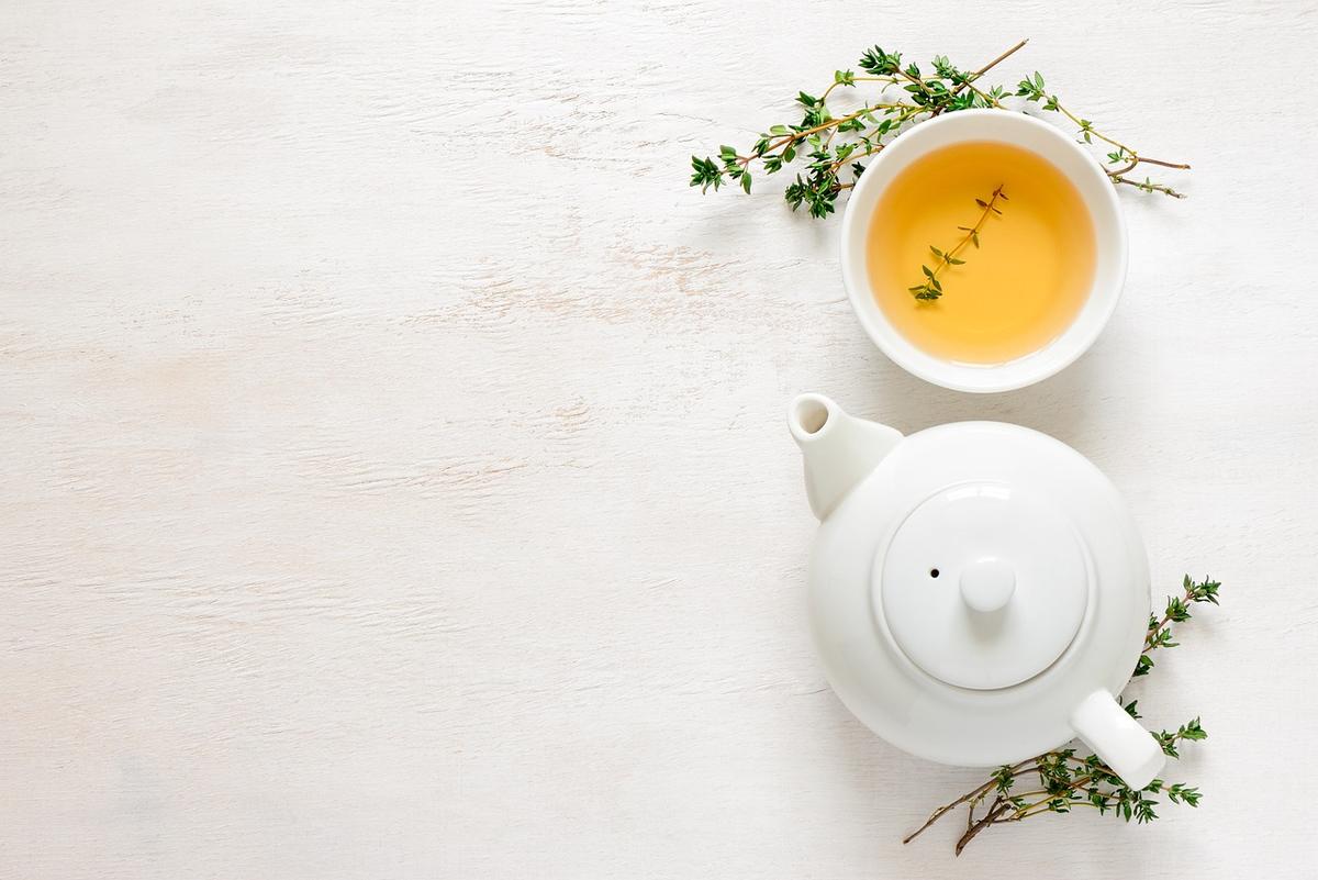 Une tasse de thé et une théière blanche sur fond blanc