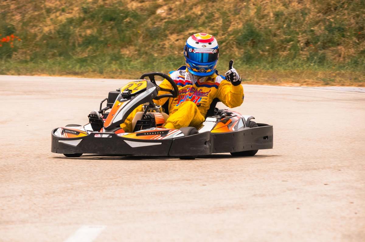 Un conducteur de karting en tenue jaune et casque bleu sur piste Un conducteur de karting en tenue jaune et casque bleu sur piste