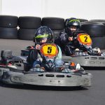 Deux jeunes pilotes dans des karting, portant casques, sur piste