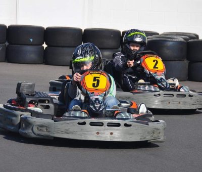 Deux jeunes pilotes dans des karting, portant casques, sur piste