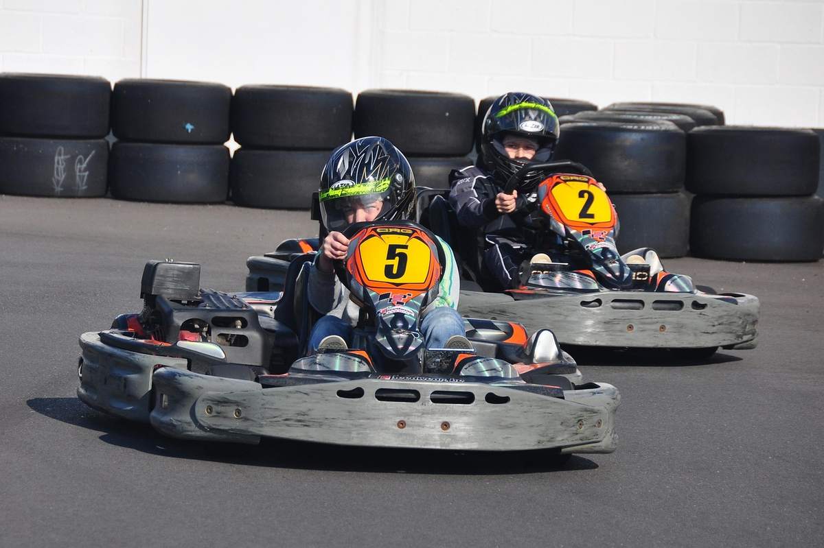 Deux jeunes pilotes dans des karting, portant casques, sur piste