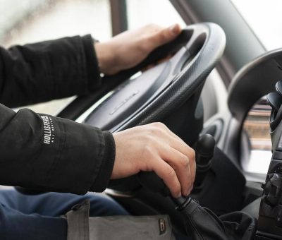 Mains sur le volant et le levier de vitesses d'une voiture