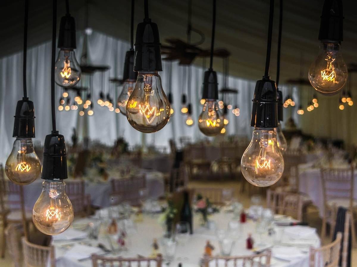 Suspension d'ampoules vintage éclairant une salle de banquet préparée Suspension d'ampoules vintage éclairant une salle de banquet préparée