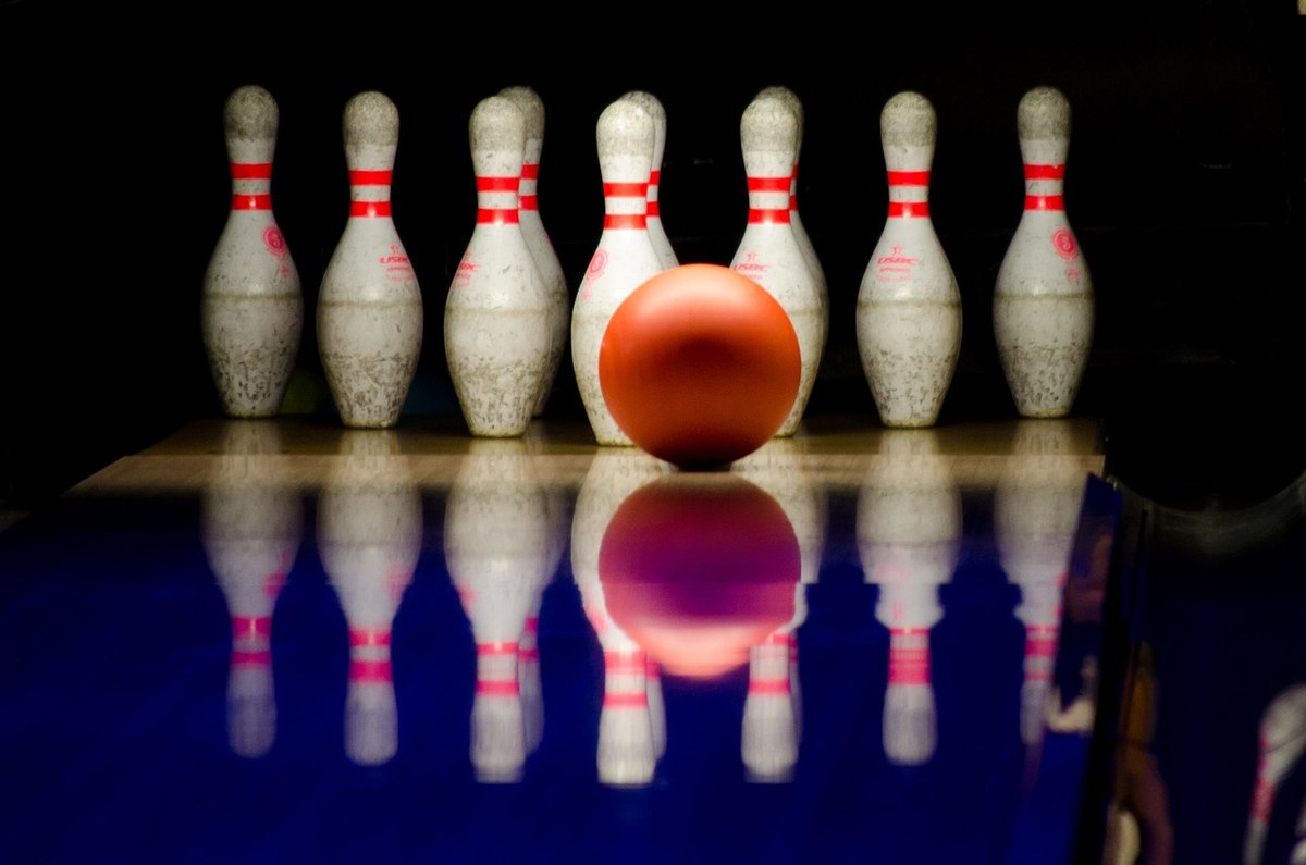 Boule rouge prête à frapper les quilles alignées sur la piste