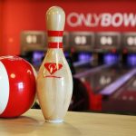 Boule rouge et quille blanche sur table, allées et panneaux visibles
