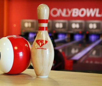 Boule rouge et quille blanche sur table, allées et panneaux visibles