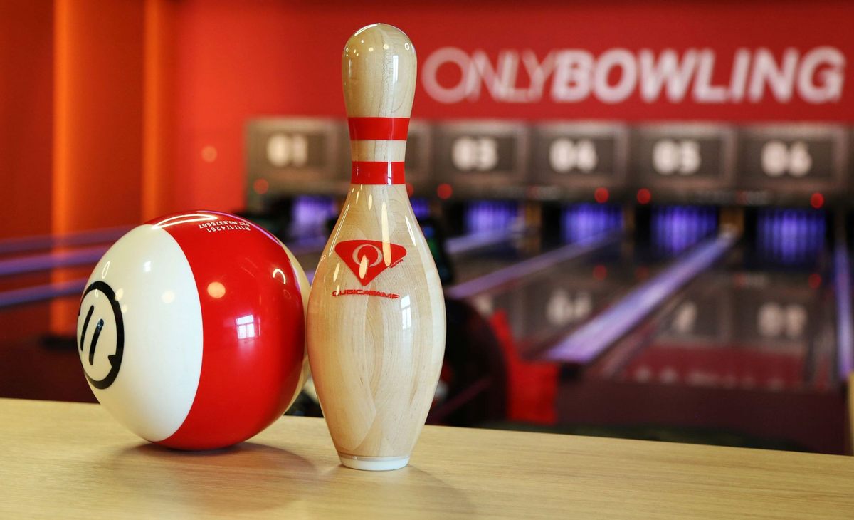 Boule rouge et quille blanche sur table, allées et panneaux visibles