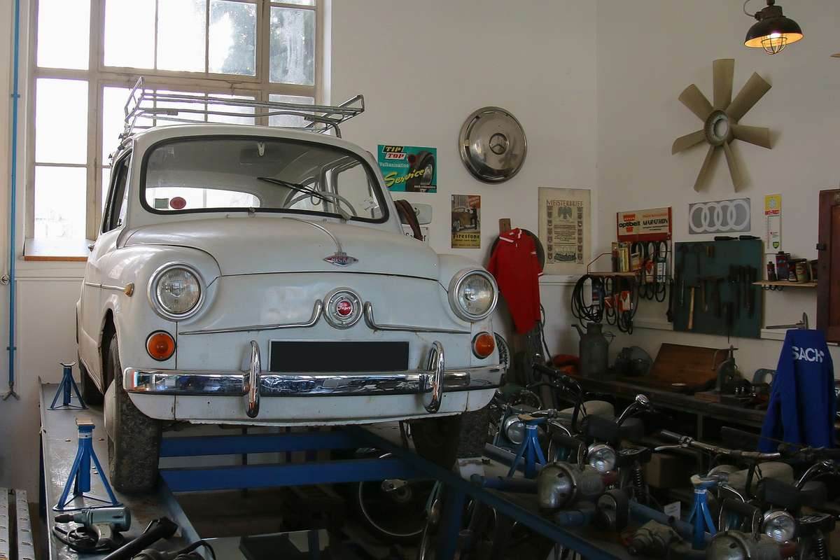 Voiture blanche vintage sur pont d'atelier, outils et pièces autour