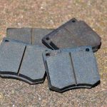 Quatre plaquettes de frein métalliques posées sur terrain granuleux