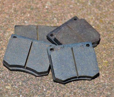 Quatre plaquettes de frein métalliques posées sur terrain granuleux