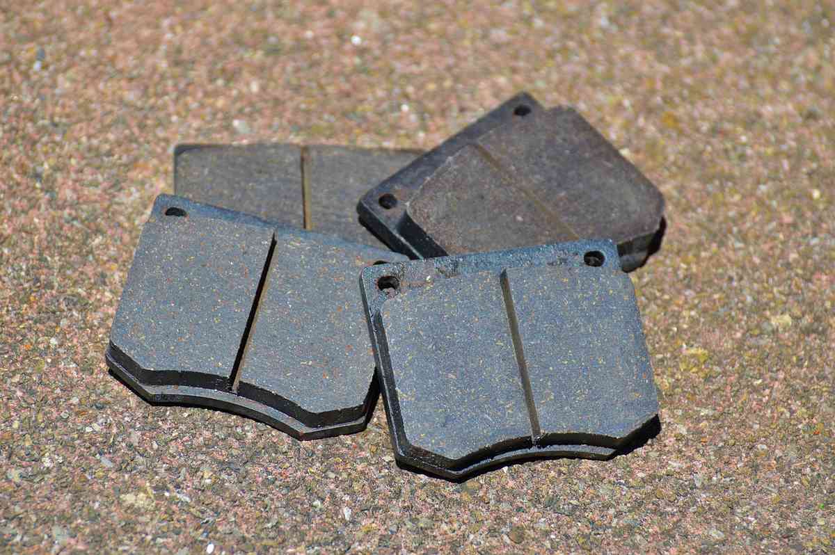 Quatre plaquettes de frein métalliques posées sur terrain granuleux